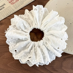 Close-up of white heart embroidery lace scrunchie on a rustic wooden table background