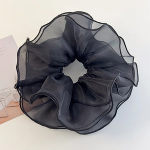 Detail of black double-layered mesh scrunchie with soft ruffled edges on white background