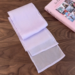 Detailed view of light purple silk scarf with vertical stripes on a wooden desk