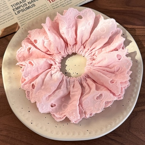 Detail of pink embroidered lace scrunchie with eyelet cutouts and ruffled edges