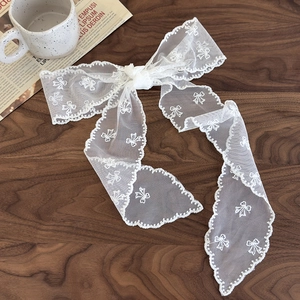 Détail de ruban à cheveux en dentelle blanche avec broderies de nœuds sur fond de bois