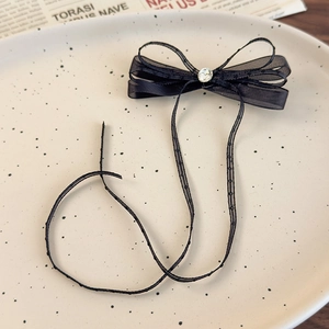 Detail of black mesh ribbon hair clip with sparkling rhinestone on ceramic tray