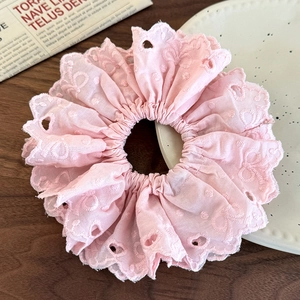 Detail of pink embroidered lace scrunchie showing delicate eyelet pattern on fabric