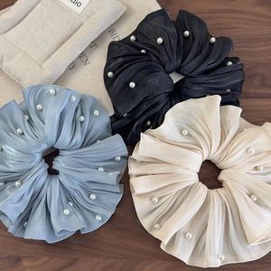 Gros plan de chouchous en soie plissée noir, bleu et beige ornés de perles délicates