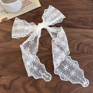 Détail d'un ruban à cheveux en dentelle brodée de fleurs sur un fond de bois foncé