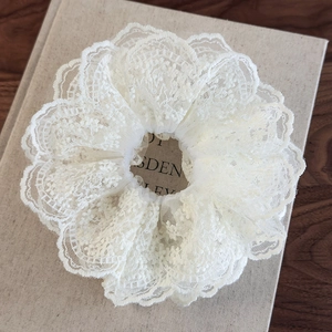 Macro detail of white multi-layer floral lace scrunchie with intricate embroidery