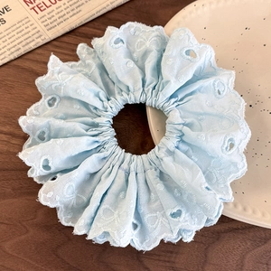 Detail of light blue lace scrunchie with hollow heart embroidery on dark wood