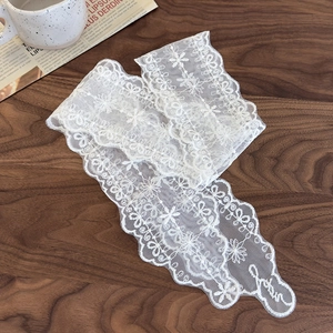 Détail macro d'un ruban en dentelle blanche avec broderie florale et tulle sur bois