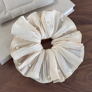 Détail d'un chouchou en satin plissé avec perles sur un fond de bois rustique