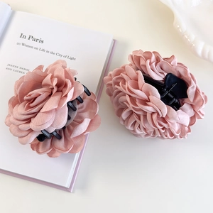 Détail de pinces à cheveux rose en tissu avec pétales superposés sur un livre