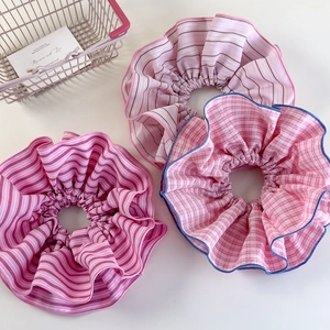 Detailed close-up of striped and checkered oversized scrunchies in soft pink tones