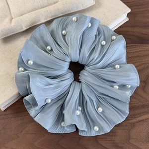 Détail d'un chouchou en satin bleu clair avec perles blanches sur bureau en bois