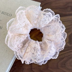 Detailed close-up of layered beige lace scrunchie with elegant floral embroidery textures