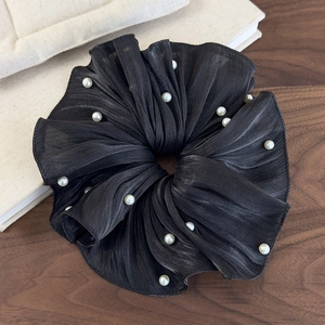 Détail d'un chouchou noir plissé en soie haut de gamme orné de perles blanches chic