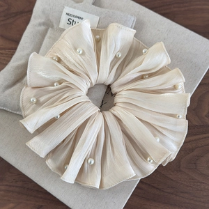 Détail d'un chouchou en satin plissé doré champagne avec perles élégantes
