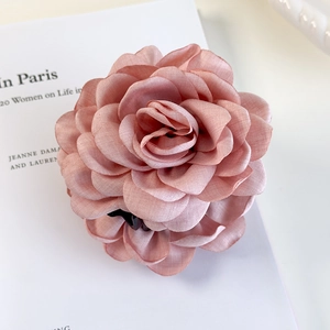 Détail d'une pince à cheveux fleur rose poudré avec pétales en tissu multicouches
