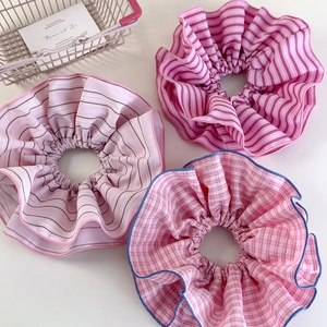 Detailed view of three pink striped and plaid scrunchies with soft ruffled fabric texture