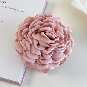 Détail d'une grande pince à cheveux rose en tissu avec pétales multicouches et finition mate