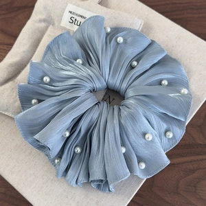 Détail d'un chouchou en satin plissé bleu clair avec d'élégantes perles blanches