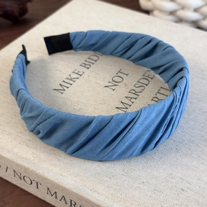 Detail of blue pleated fabric headband with vintage diagonal stripes on a book