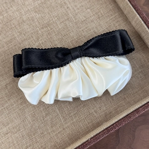 Detail der Vintage-Haarklammer mit schwarzen Wellenkanten und cremefarbener Satinfalte