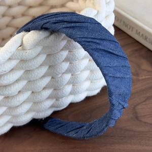 Detailed macro view of deep blue denim headband with elegant pleated texture and fabric