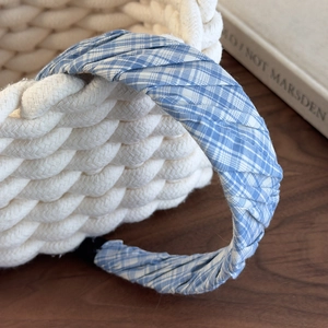 Detail of blue and white plaid fabric headband with pleated texture on a woven basket