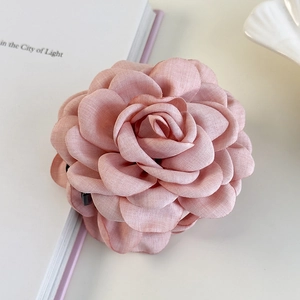 Eleganter rosa Kamelien-Haarclip aus Stoff für Damen auf minimalistischem Schreibtisch