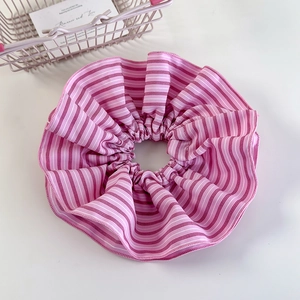 Detailed view of a pink and white striped large fabric scrunchie with soft pleats