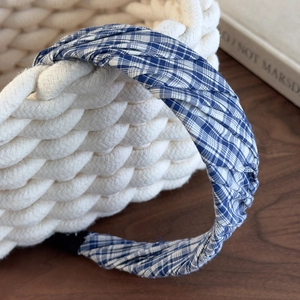 Close-up of blue and white checkered headband with pleat details on woven basket