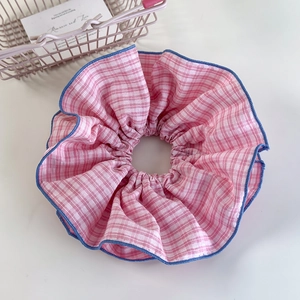Close-up of pink and white checkered fabric scrunchie with blue stitched edges and high texture