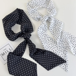 Detail of narrow black and white polka dot silk scarves in elegant knotted styling
