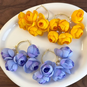 Floral hoop earrings with layered fabric petals and pearls in yellow and purple