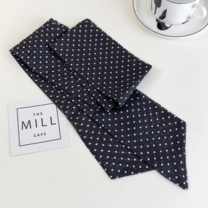 Detail of long black neck scarf with white polka dots featuring lightweight fabric texture