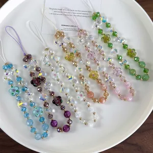 Colorful handmade beaded phone charms with crystal flowers and bows in a tray