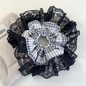 Detail of checkered scrunchie with delicate black lace trim on white background