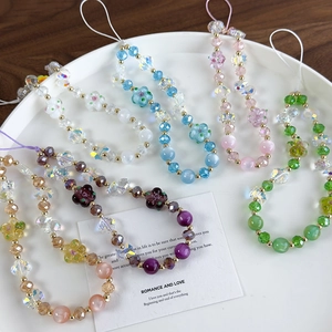 Detailed macro view of colorful handmade beaded phone charms with flowers on a white plate