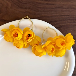 Detailed macro view of yellow fabric rose petals on gold hoop earrings with small white pearls