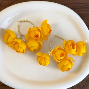Detail of yellow fabric flower hoop earrings with pearls for vacation styling