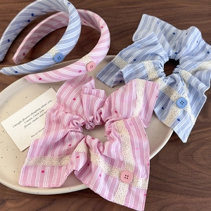 Accessoires cheveux rayés rose et bleu avec dentelle et boutons sur un plateau