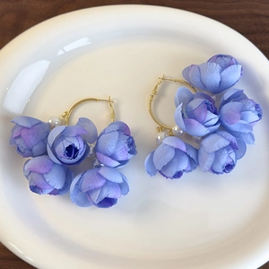Detailed shot of lavender fabric rose earrings with white pearls on a gold metal hoop