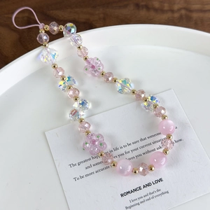 Detail of pink cat-eye stones, faceted crystal beads and resin flower on a phone strap