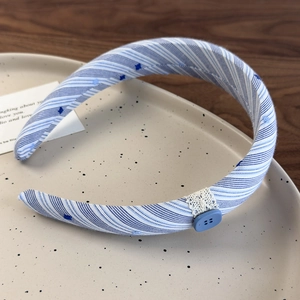 Détail du serre-tête en tissu à rayures bleues avec dentelle blanche et bouton