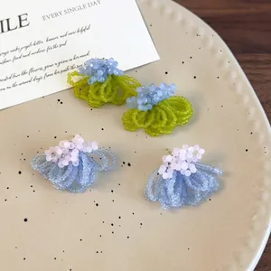 Handmade frosted crystal bead flower earrings in green and blue on a ceramic tray