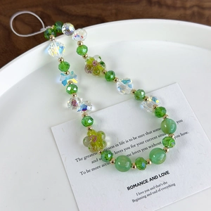 Detail of beaded phone strap with green glass beads, aurora butterfly, and flower charms