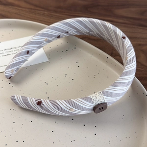 Détail du bandeau en tissu rayé avec dentelle et bouton sur une assiette en céramique