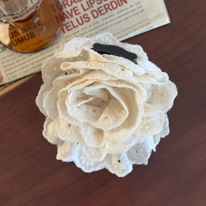 Macro shot of sweet cream lace rose hair claw with delicate embroidery on dark wood