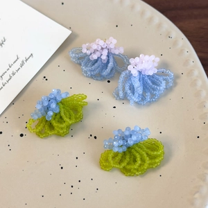 Detail view of handmade frosted crystal beaded stud earrings in pastel blue and green