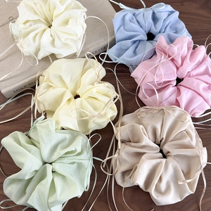 Lot de six chouchous colorés en organza avec rubans sur une table en bois