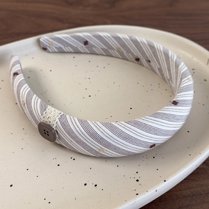 Détail d'un serre-tête vintage en tissu avec bouton en résine et dentelle beige fine